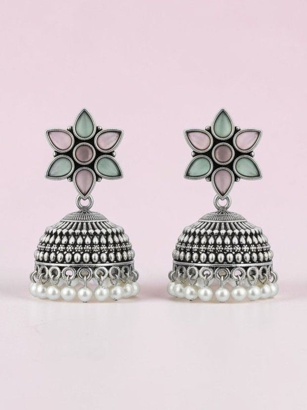Oxidised silver flower stud jhumka earrings with pearl fringe displayed against soft pink background
