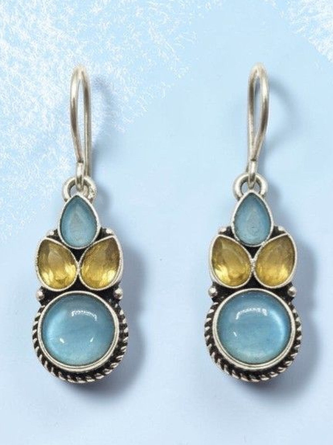 Oxidised silver blue and yellow stone drop earrings displayed on a light blue background showing full detail