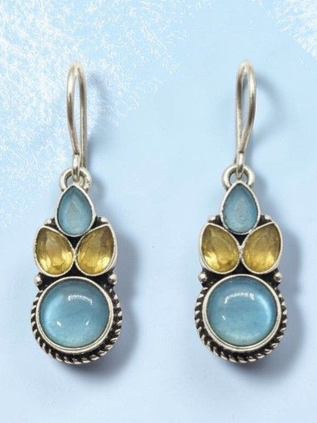 Oxidised silver blue and yellow stone drop earrings displayed on a light blue background showing full detail