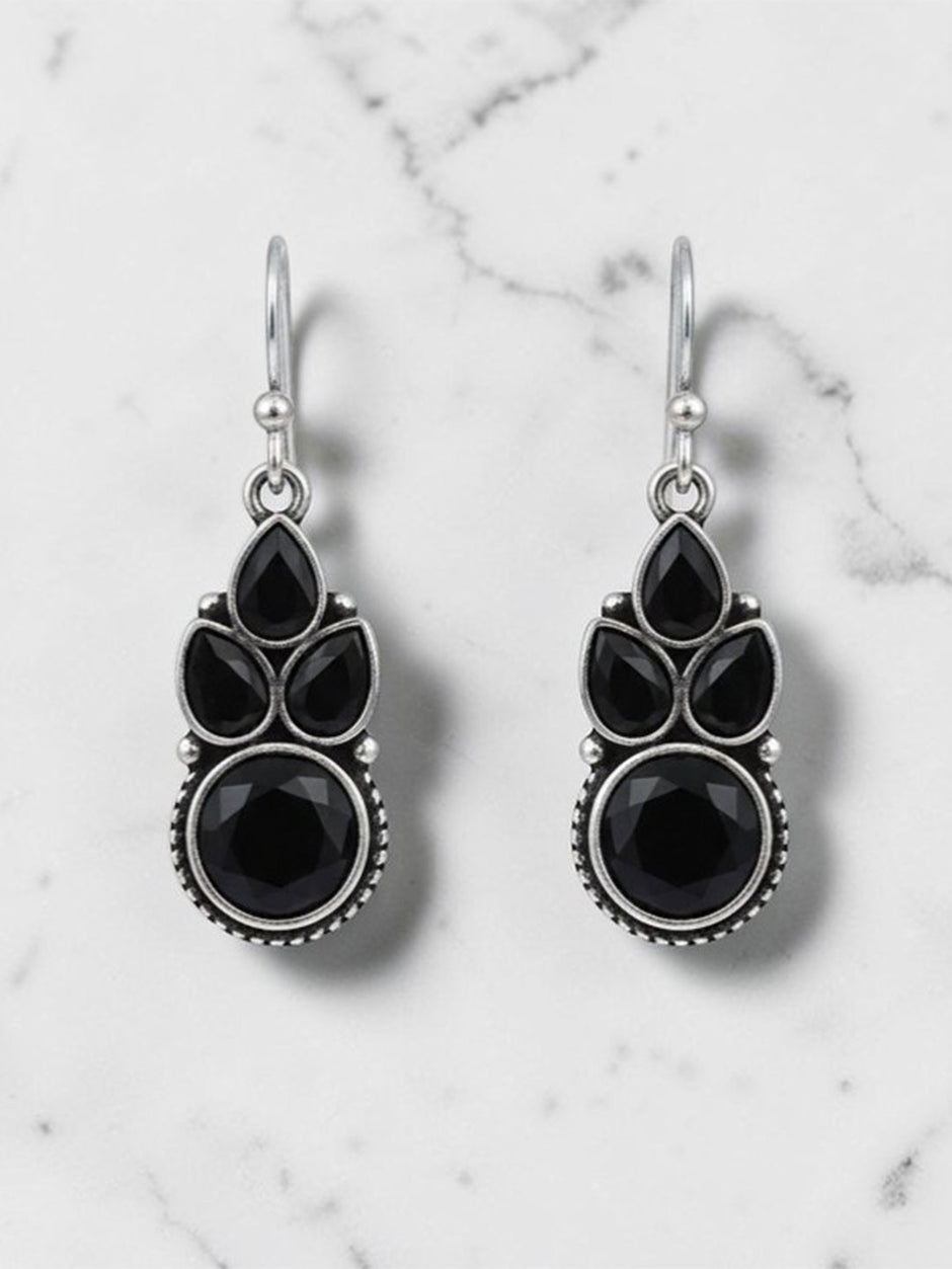 Pair of oxidised silver drop earrings with black pear and round stones on white marble background