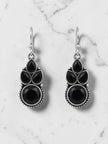 Pair of oxidised silver drop earrings with black pear and round stones on white marble background