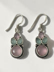 Pair of oxidised silver drop earrings with blush pink and sage green cabochon stones on white background