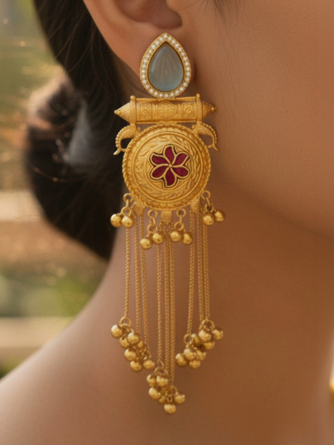 Gold-plated meenakari chandbali earring worn on ear showing cascading ghungroo chains and red floral enamel disc