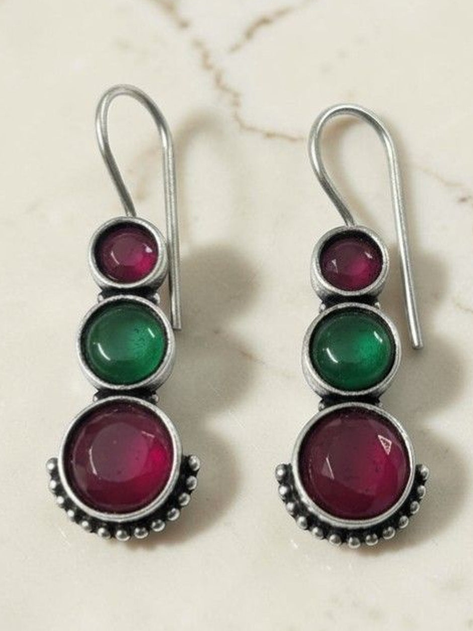 Oxidised silver three-stone drop earrings with shepherd-hook wires on a marble background