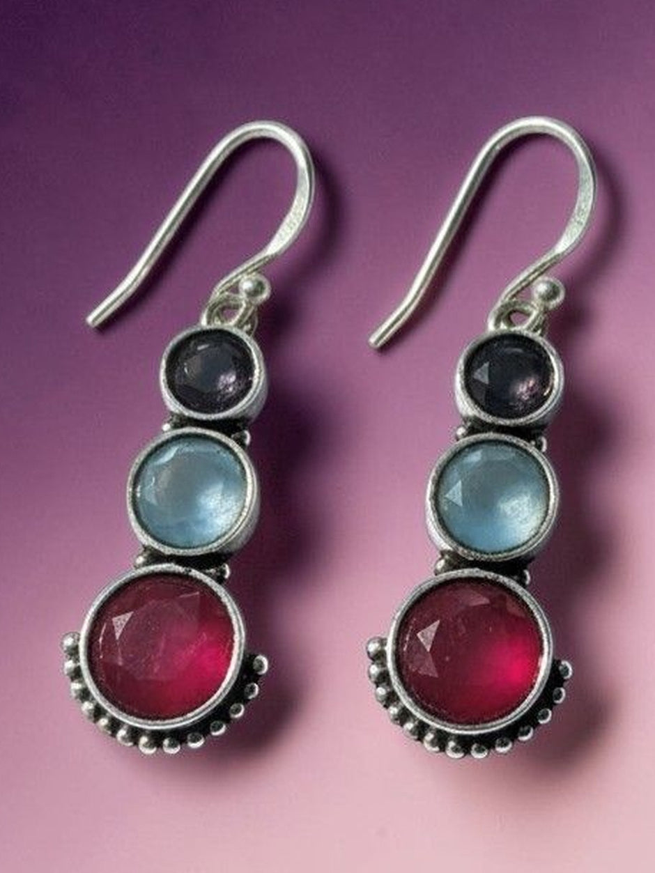 Oxidised silver triple stone drop earrings displayed against a purple gradient background showing colour contrast