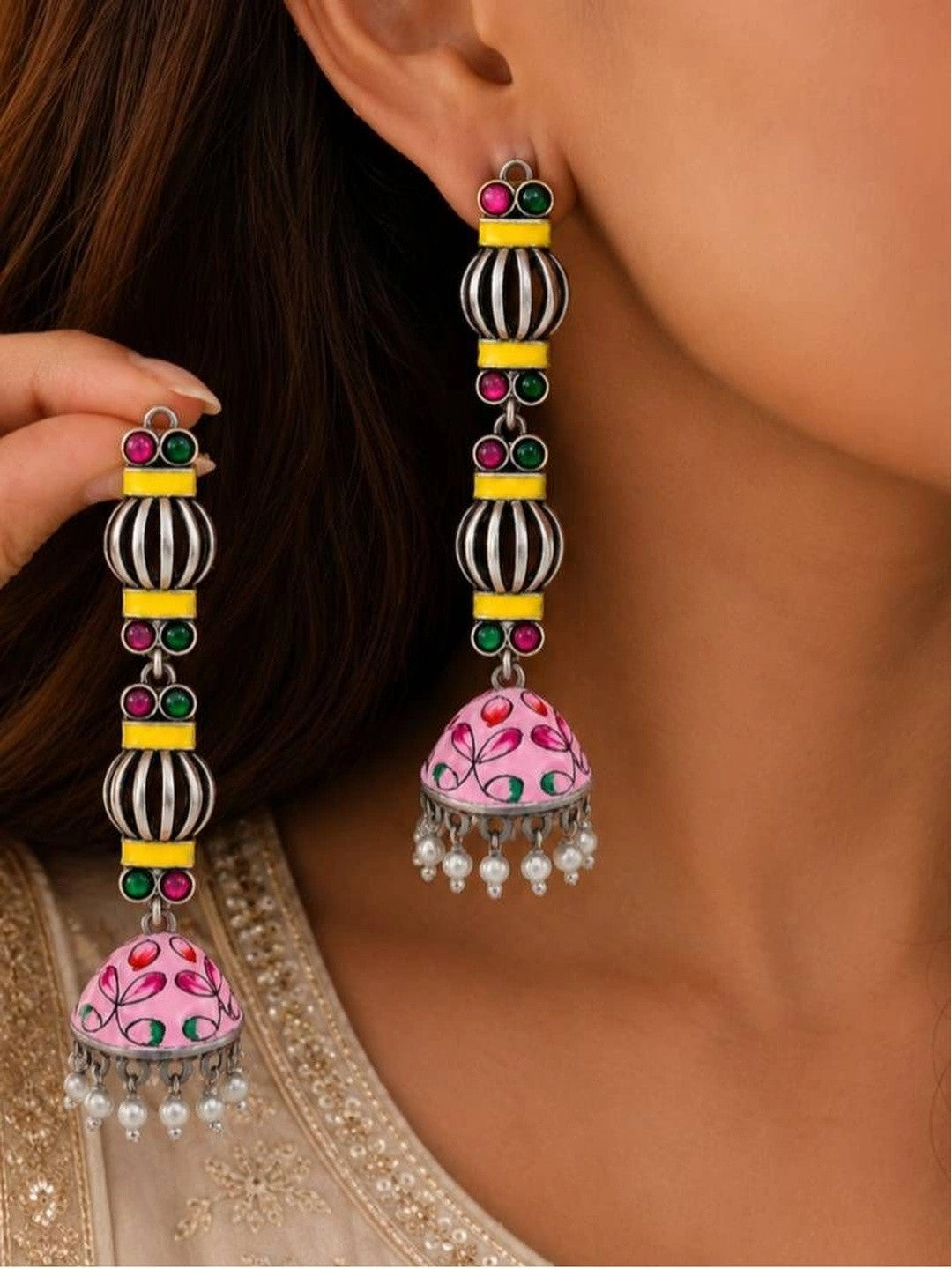 Model wearing long oxidised silver geometric jhumka earrings with pink enamel dome and pearl drops at the ear