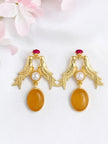 Pair of gold-plated love birds drop earrings with amber oval drop and pink crystal stud on white background