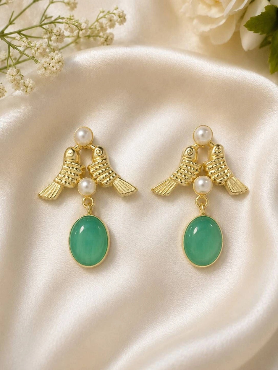Pair of gold-plated twin bird drop earrings with pearl beads and oval green stone pendants on cream satin fabric