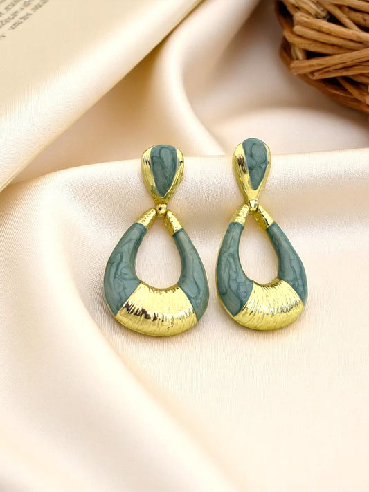 Gold and green earrings on a beige fabric background & this earrings is the best earrings for woman.