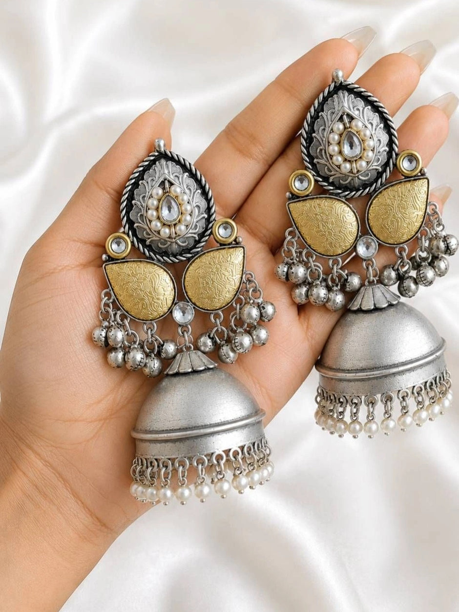 Two oxidised silver jhumka earrings resting on an open palm showing full length and gold-tone panels
