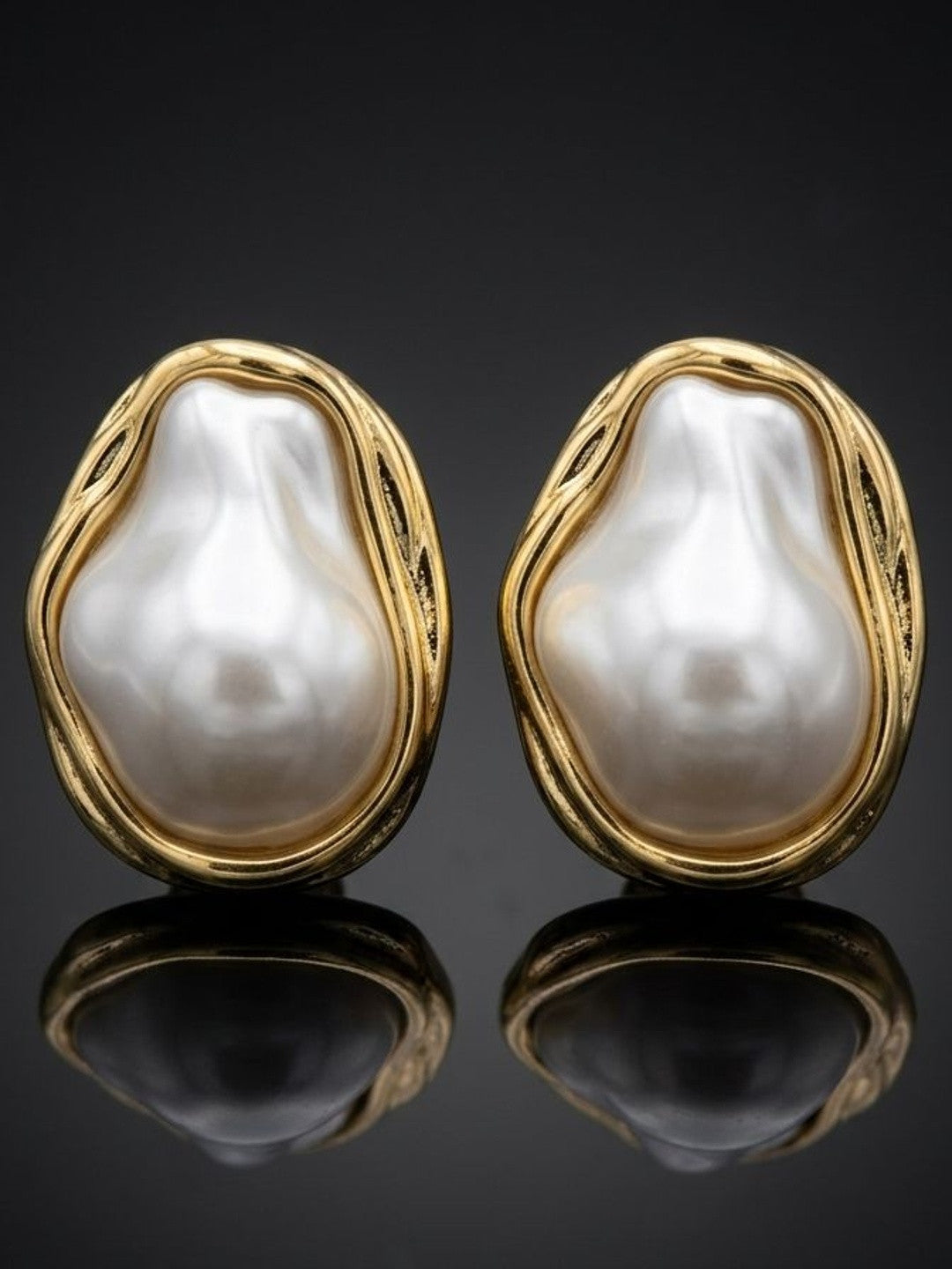 Pair of gold-plated baroque pearl stud earrings on dark reflective surface