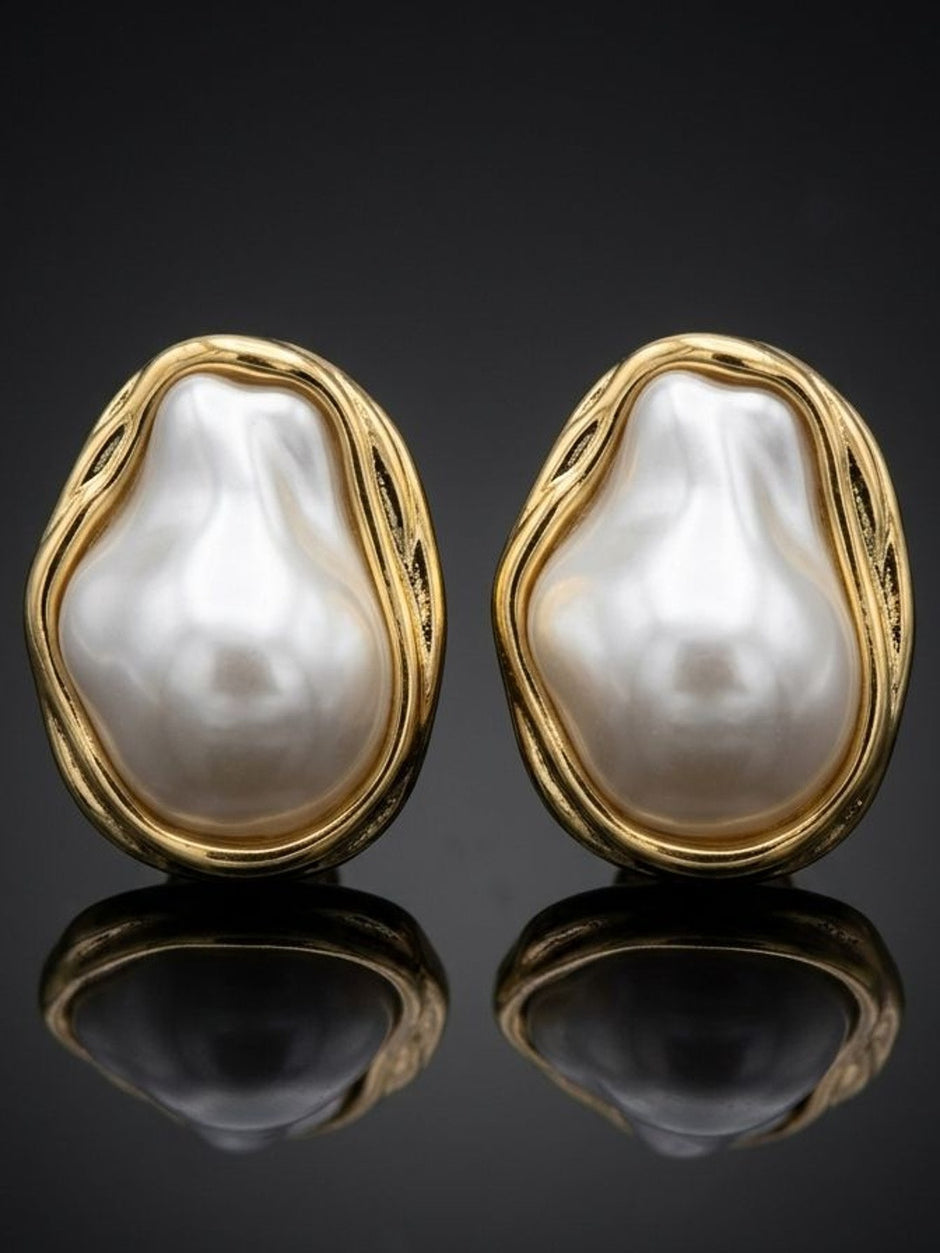 Pair of gold-plated baroque pearl stud earrings on dark reflective surface
