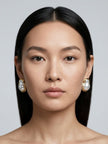 Model facing forward wearing gold baroque pearl stud earrings on both ears
