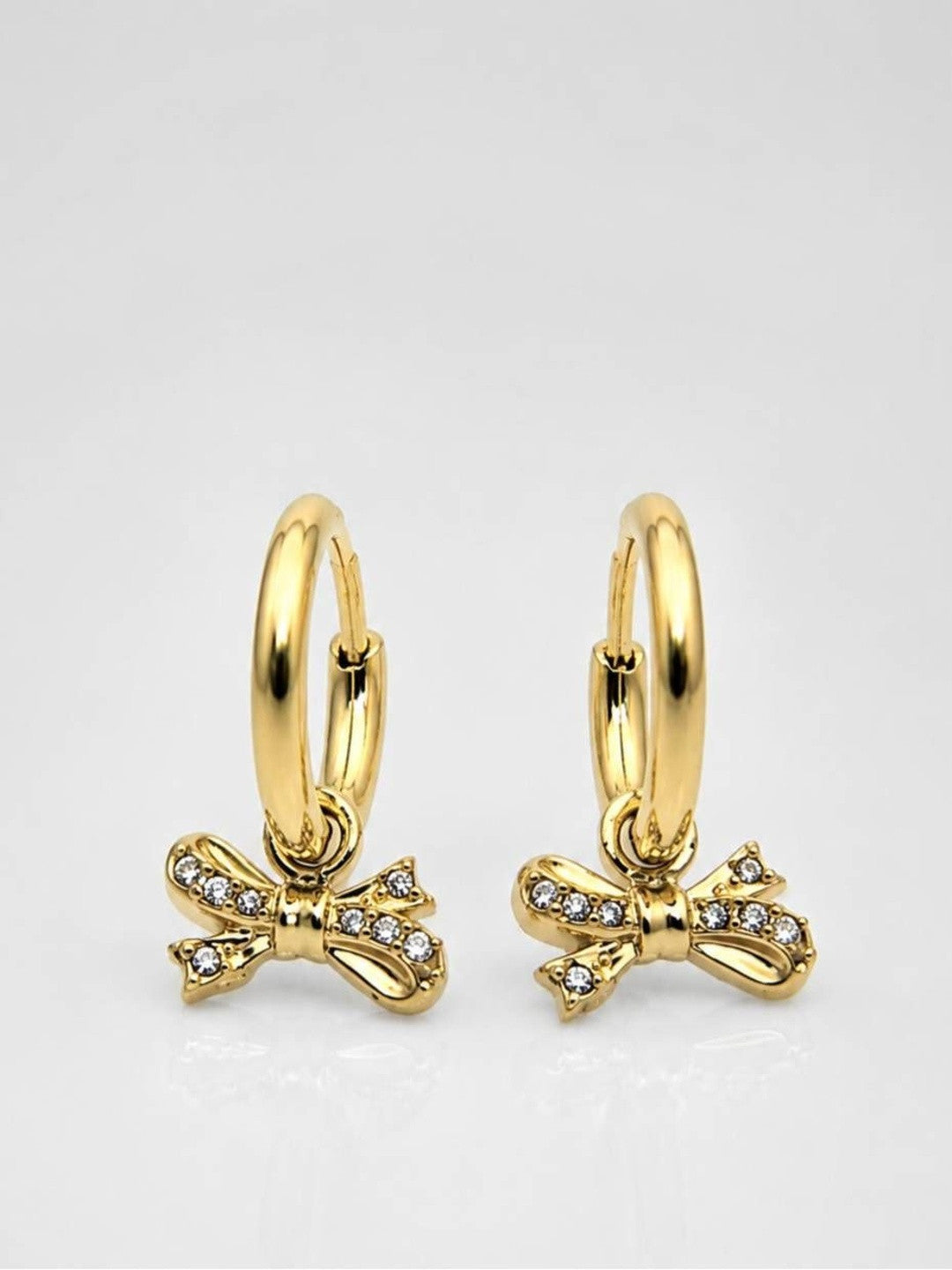 Two gold-plated bow charm hoop earrings displayed on white surface showing front and back angle