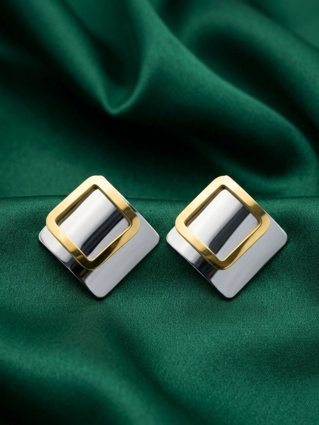 Pair of two-tone square stud earrings with gold-finish open frame on silver base, displayed on green satin fabric