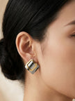 Side profile of a woman with black hair wearing a two-tone silver and gold geometric square stud earring