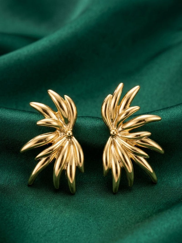 Pair of gold-plated floral burst stud earrings displayed on deep green satin fabric