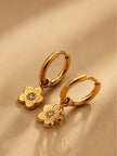 Pair of gold-plated flower charm hoop earrings with engraved petals and crystal centre on beige background