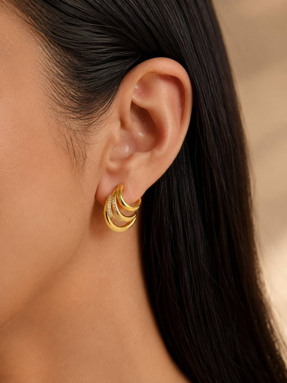 Close-up of gold multi-hoop earring worn on a model with dark hair showing scale and fit