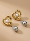 Pair of gold-tone open-heart earrings with faux pearl centre and silver teardrop pendants on beige surface
