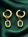 Pair of gold-plated emerald green cushion drop hoop earrings laid flat on dark green satin fabric