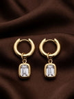 Pair of gold-plated chunky hoop earrings with emerald-cut crystal bezel charms on brown silk fabric