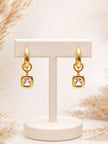 Gold-plated hoop earrings with clear crystal cushion pendants displayed on white jewellery T-bar stand