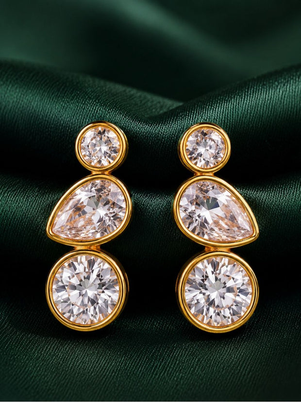 Pair of gold-plated bezel drop earrings with round pear and round crystal stones on green satin