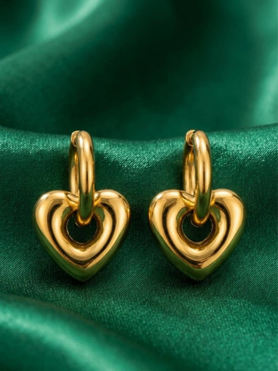 Pair of gold-plated open heart drop hoop earrings displayed on green satin fabric