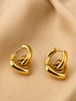Gold heart charm hoop earrings lying flat on beige fabric showing hinge closure detail