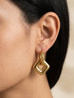 Angled view of gold hoop and hollow square drop earring worn on model showing full pendant detail