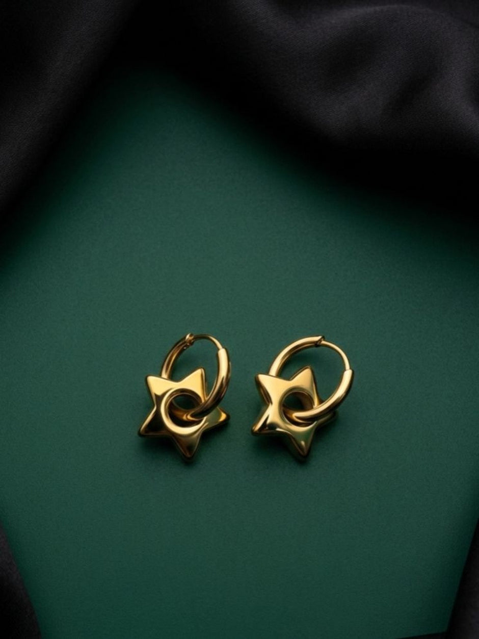Pair of gold-plated star charm hoop earrings displayed flat on dark green surface