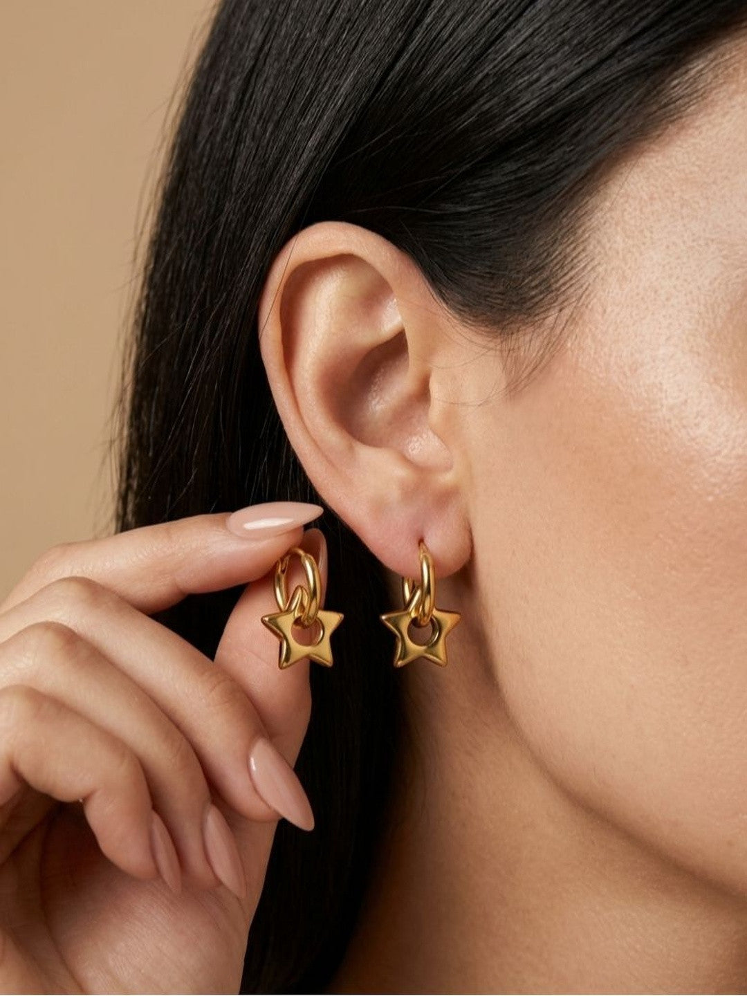 Model holding gold star hoop earrings near both ears showing front and side detail