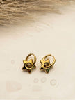 Pair of gold star charm hoop earrings laid on neutral textured surface with dried grass backdrop