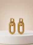 Pair of gold-plated ribbed oval link drop earrings standing upright on a white display pedestal