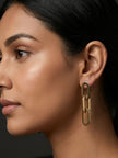 Side profile of woman wearing gold three-link chain drop earring against a dark background