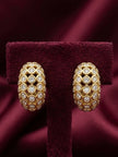 Pair of gold-plated dome hoop earrings covered in bezel-set crystal stones displayed on burgundy velvet earring stand