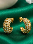 Two gold-plated crystal bezel hoop earrings placed on emerald green satin fabric showing open lattice underside