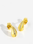 Side angle of gold-plated teardrop stud earrings showing depth of dome and zirconia channel setting on white surface