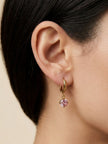 Gold hoop earring with pink stone charm worn on a woman's ear, side profile view