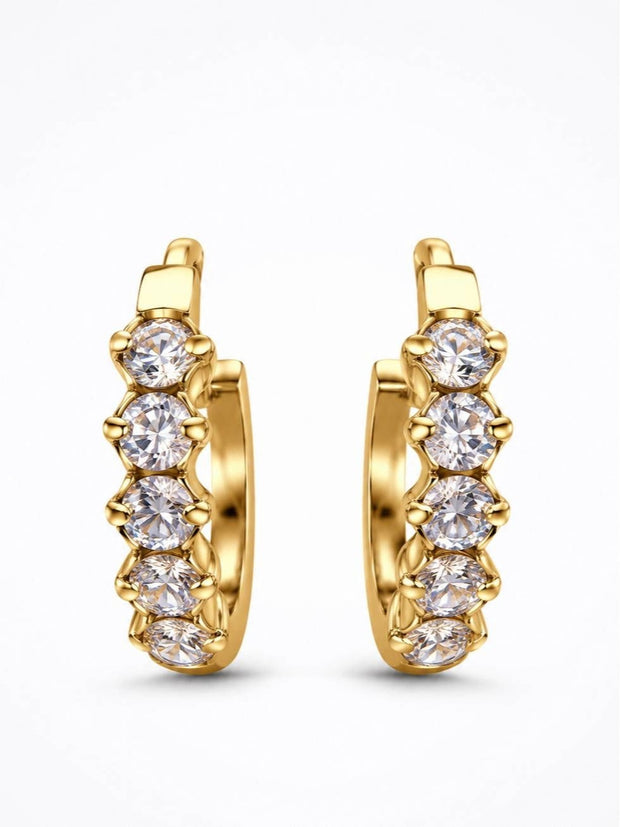 Pair of gold-plated huggie hoop earrings with five round prong-set cubic zirconia stones on white background