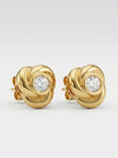 Close-up of gold-plated knot stud earrings showing spiral detail and bezel-set crystal on white background