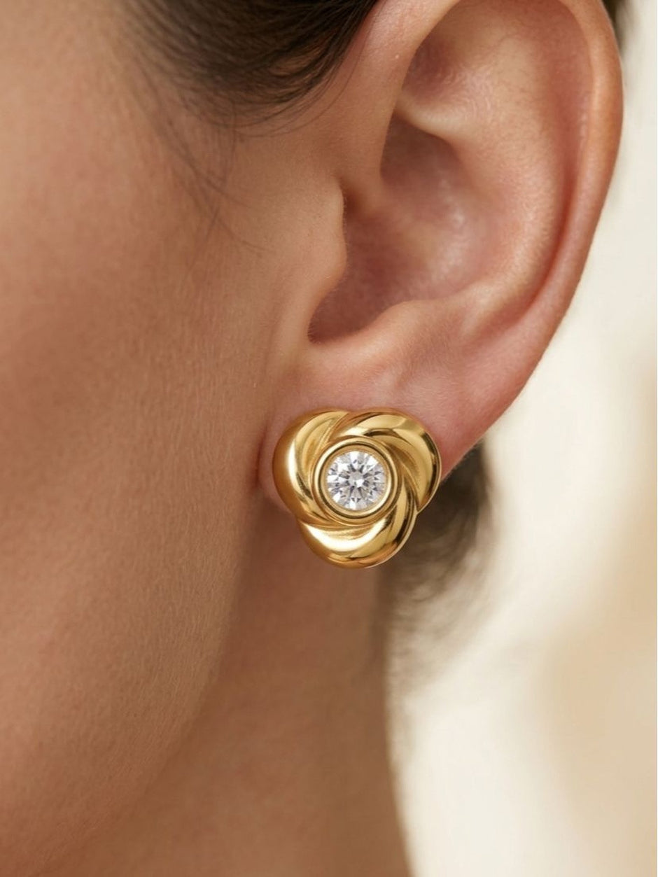 Gold swirl knot stud earring worn on a woman's earlobe showing scale and fit
