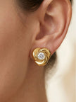 Gold swirl knot stud earring worn on a woman's earlobe showing scale and fit
