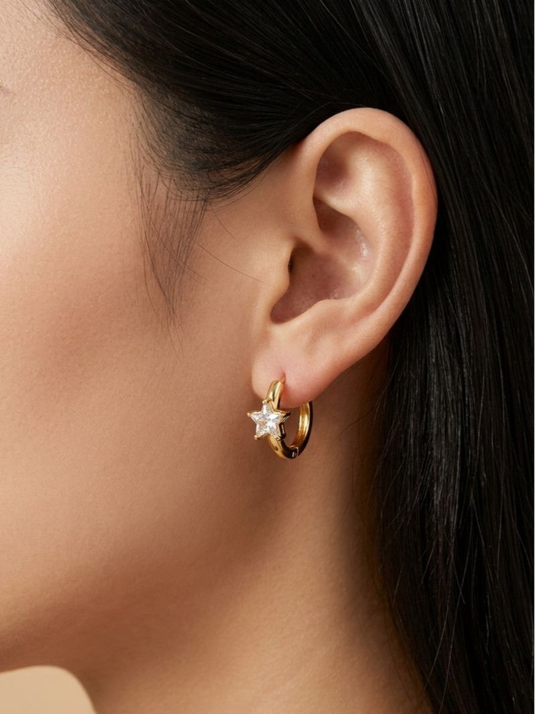 Gold-plated star zirconia hoop earring worn on a woman's ear, side profile view