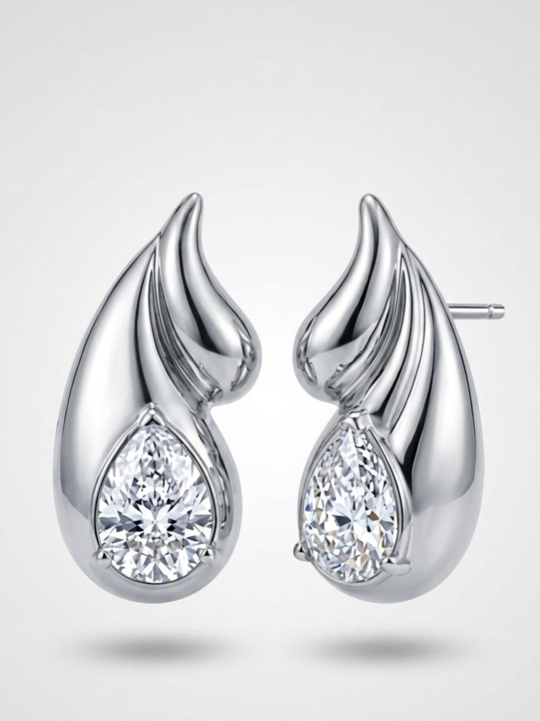 Pair of silver-tone flame wing stud earrings with pear-cut crystal stones on white background