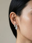 Silver flame wing crystal stud earring worn on a woman's ear, side profile close-up