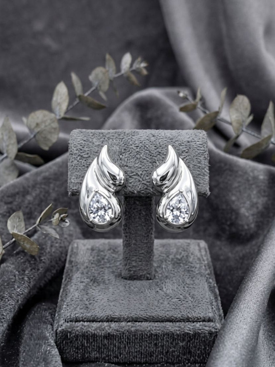 Silver flame wing crystal stud earrings displayed on a grey velvet jewellery stand with eucalyptus sprigs