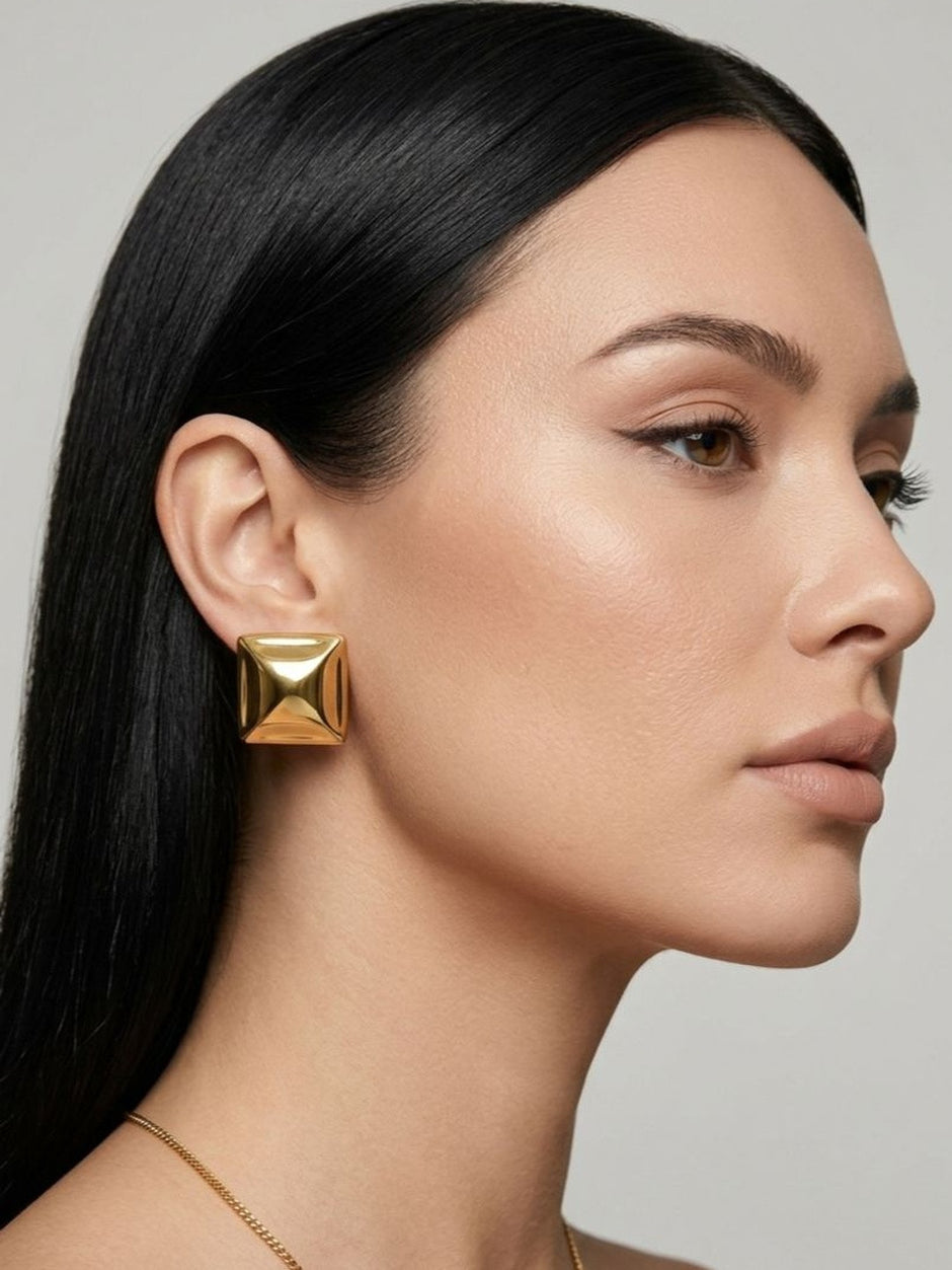 Model wearing gold square pyramid stud earring with sleek straight dark hair