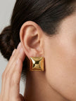 Close-up of gold pyramid square stud earring worn on a woman's ear